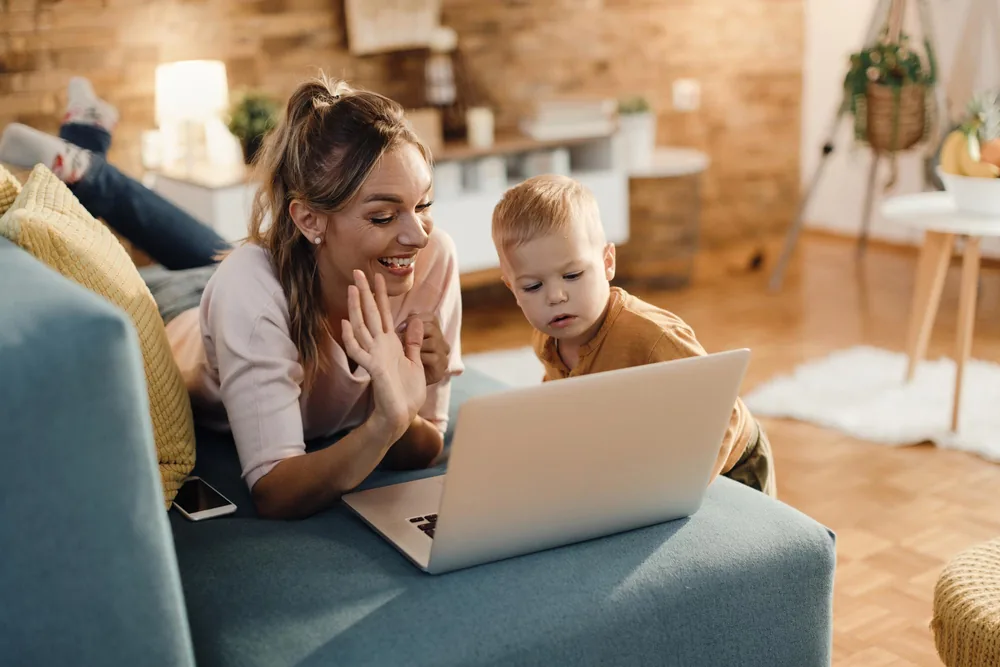 Mother smiling while using a laptop at home