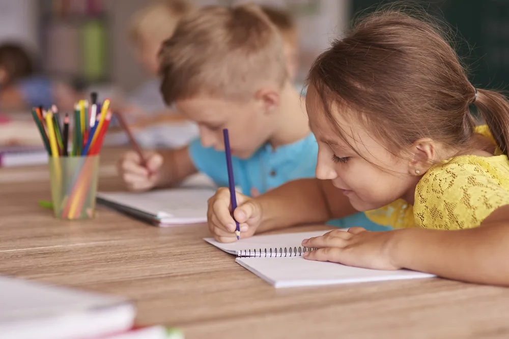 Kids writing notes together and smiling