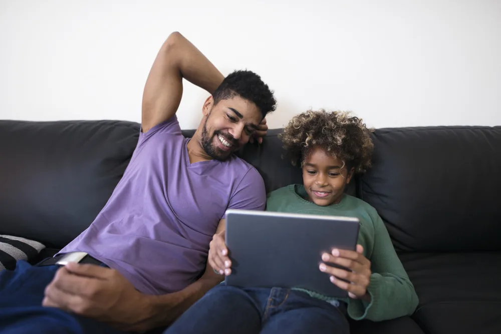 Parent and child looking at a tablet together on the couch